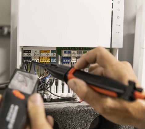 Die Anschlüsse einer Wärmepumpe werden von einem Rieber Mitarbeiter geprüft