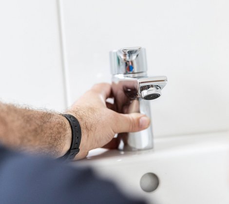 Rieber Mitarbeiter schließt einen Wasserhahn an ein Waschbecken an